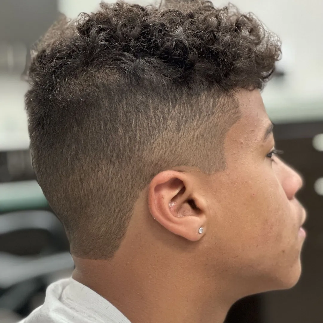 Haircut by Geraldo Barber: textured curly top with a skin fade
